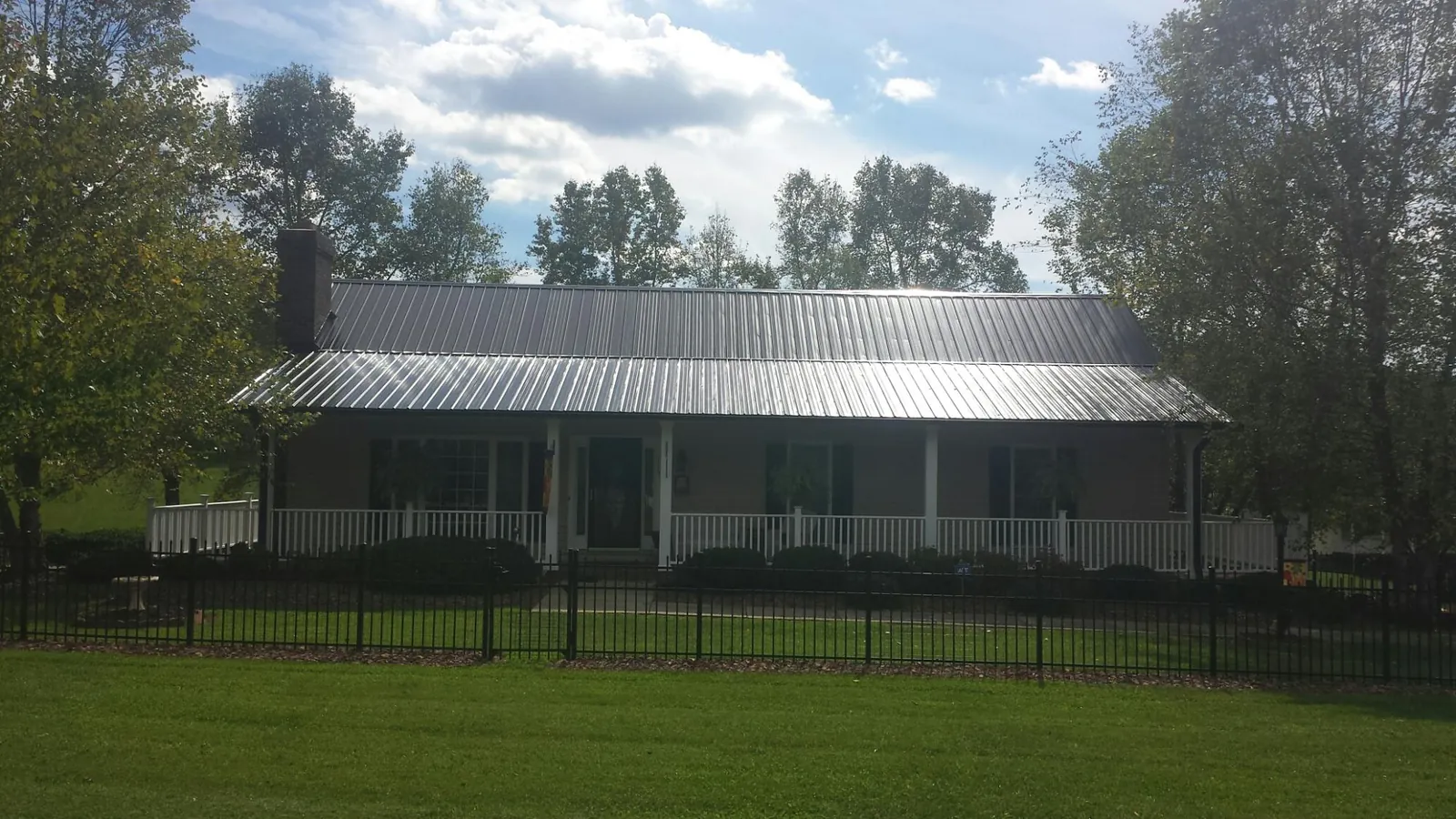 Gray metal roof on a brick ranch with a full width front porch — Gutter Guard Installation work by our crew in Ellsworth